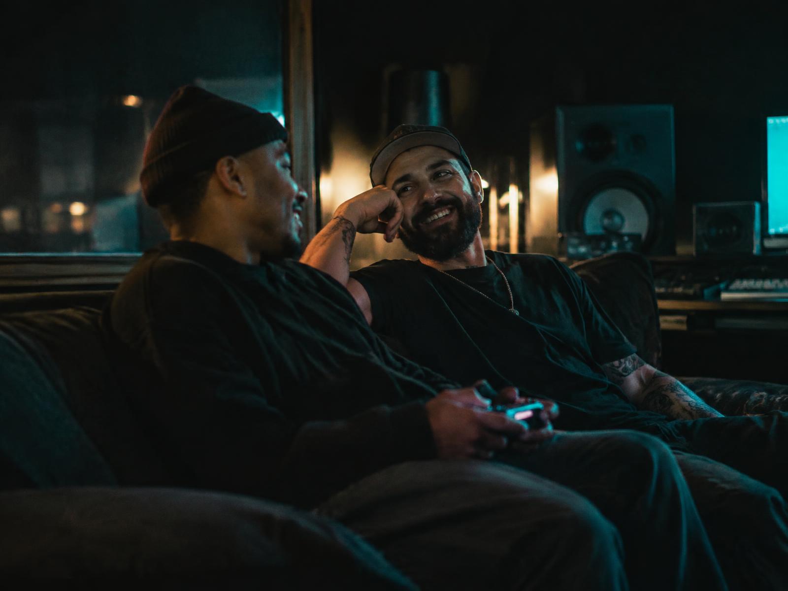 Two men talking and laughing together in a dimly lit studio lounge